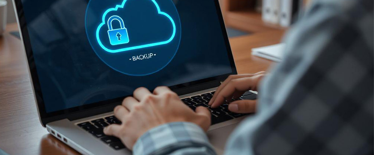 A person working on a laptop, with visible signs of a backup process or cloud backup activity displayed on the laptop screen